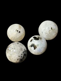 three white rocks sitting next to each other on top of a black surface with one rock in the middle