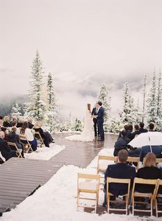 a bride and groom standing at the end of their wedding ceremony in front of a snowy mountain