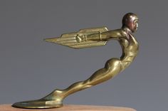 a gold statue holding a wooden object in it's right hand and pointing to the left