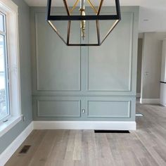 an empty room with gray walls and wood flooring in the center is a chandelier