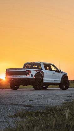 a white truck driving down a road at sunset