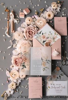 the wedding stationery is laid out on top of flowers and confetti scattered around it