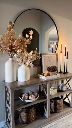 a table with vases and candles on top of it in front of a mirror