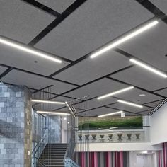 the interior of a building with some stairs and lights on it's ceiling, in front of a stone wall