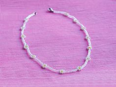 a white beaded bracelet on a pink surface