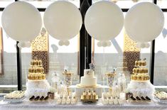 a table topped with lots of white and gold balloons