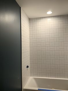 a bath tub sitting next to a white tiled wall