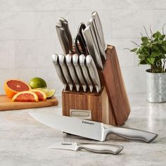 a knife holder with knives and grapefruits on a marble counter next to a cutting board