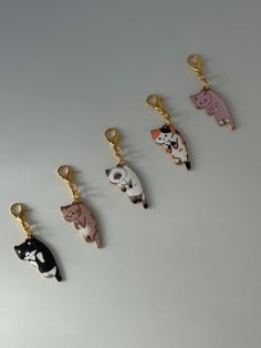 five different animal key chains on a white surface with one black cat, the other pink