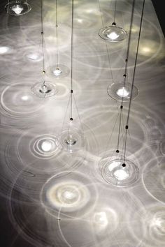 three hanging lights are suspended from strings with circles on the ceiling and circular light bulbs above them