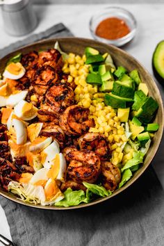 a bowl filled with shrimp, corn and avocado on top of a table