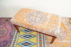 an orange bench sitting on top of a colorful rug