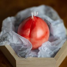 a red apple sitting inside of a wooden box on top of a white paper bag