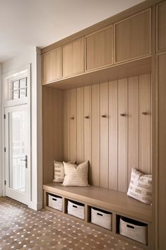 a wooden bench sitting in the middle of a room next to a white door and window