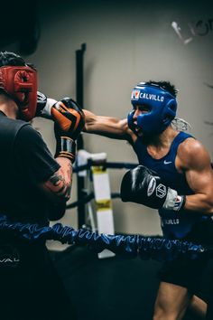 two men are boxing in the ring with gloves on their heads and one is wearing blue