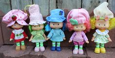 a group of little dolls standing next to each other on a brick wall in front of a wooden fence