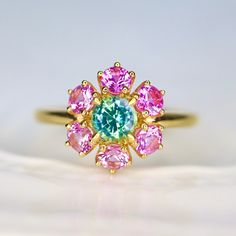 Teal sapphire cluster Ring with Pink Sapphires Natural Teal Green and Pink Ring Dainty Halo pink gemstone ring. 14K Yellow Gold US 7 RTS Discover the elegance and charm of our custom-made halo floral ring, meticulously crafted in 14K yellow gold. This exquisite piece features a harmonious blend of vibrant sapphires, designed to capture attention and add a touch of sophistication to any jewelry collection. Features: 🌟 Teal Greenish Blue Sapphire: The centerpiece of this ring, this captivating sa Pink Cluster Multi-stone Jewelry, Pink Multi-stone Cluster Jewelry, Pink Gemstone Cluster Ring, 14k Gold Green Multi-stone Cluster Ring, Pink Emerald Ring For Wedding, Pink Multi-stone Cluster Ring As A Gift, Pink Emerald Ring For Gift, Fine Jewelry, Pink Emerald Ring Fine Jewelry Gift, Pink Emerald Ring Fine Jewelry