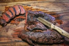 a steak is being sliced on a wooden cutting board with a knife in the middle