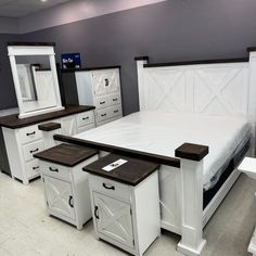 a white bed sitting in a bedroom on top of a floor next to two dressers