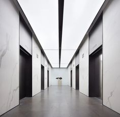 an empty hallway with white walls and black doors