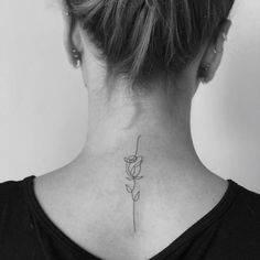 a woman's back neck with a single flower tattoo on her left side ribcage