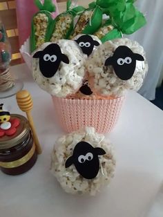 three sheep made out of rice sitting on top of a table next to a vase filled with flowers