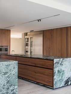 a kitchen with marble counter tops and wooden cabinets in the center, along with an island