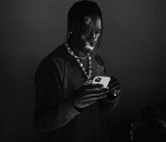 a man with his face painted in black and white, holding a cell phone while wearing a necklace