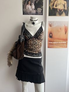 a mannequin wearing a skirt and top with pictures on the wall behind it