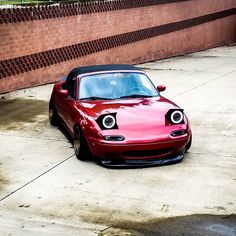 a red sports car parked in front of a brick wall