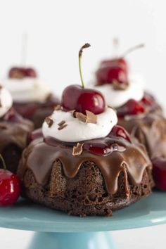 chocolate cake topped with whipped cream and cherries on a blue plate next to strawberries