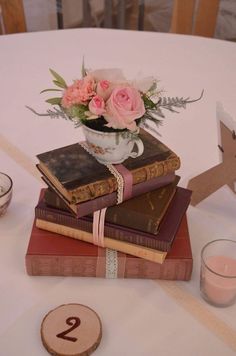 a stack of books sitting on top of each other next to a cup with flowers in it