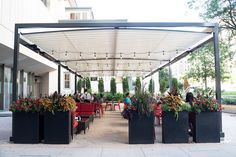 people are sitting at tables under an awning