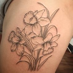 a black and white photo of some flowers on a woman's thigh with tattoos