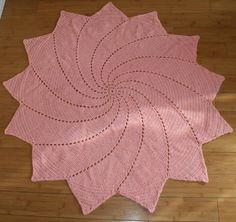 a pink rug is sitting on the floor in front of a wooden floor with an intricate design