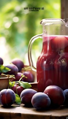 a pitcher filled with liquid next to plums