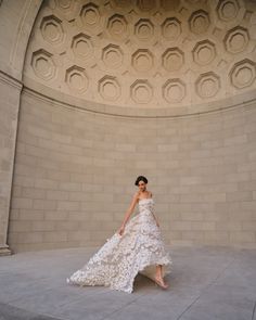 a woman in a white dress is standing near a wall