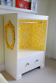 a white dresser with yellow flowers on it and a mirror mounted to the wall next to it