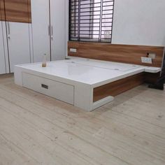 a white bed sitting in the middle of a bedroom next to a wooden floor and window