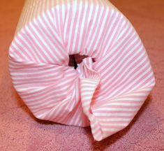 a pink and white striped cloth wrapped in a knot on the floor with a black button