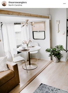 a living room filled with furniture and a white table in front of a window on top of a hard wood floor