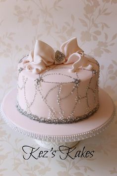 a pink cake decorated with pearls and bows