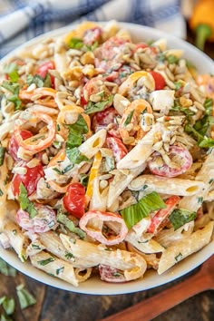 a bowl filled with pasta salad on top of a wooden cutting board