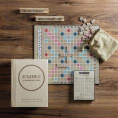 the scrabble board game is laid out on a wooden table next to its contents