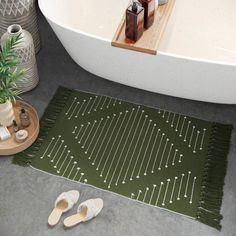 a pair of slippers sitting on top of a rug next to a bath tub