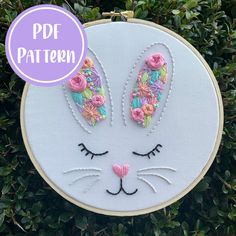 a close up of a hoop hanging on a wall with an embroidered bunny face and flowers