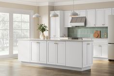 a large kitchen with white cabinets and wood flooring is pictured in this image, there are two vases on the island