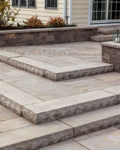 an outdoor patio with steps leading up to the front door and landscaping area behind it