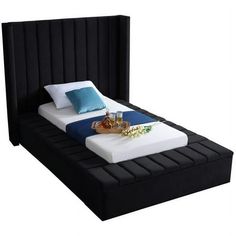 a black bed with blue and white pillows on it's headboard is shown