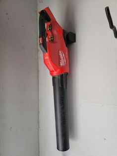 a red and black tool is hanging on the wall next to a wrench holder